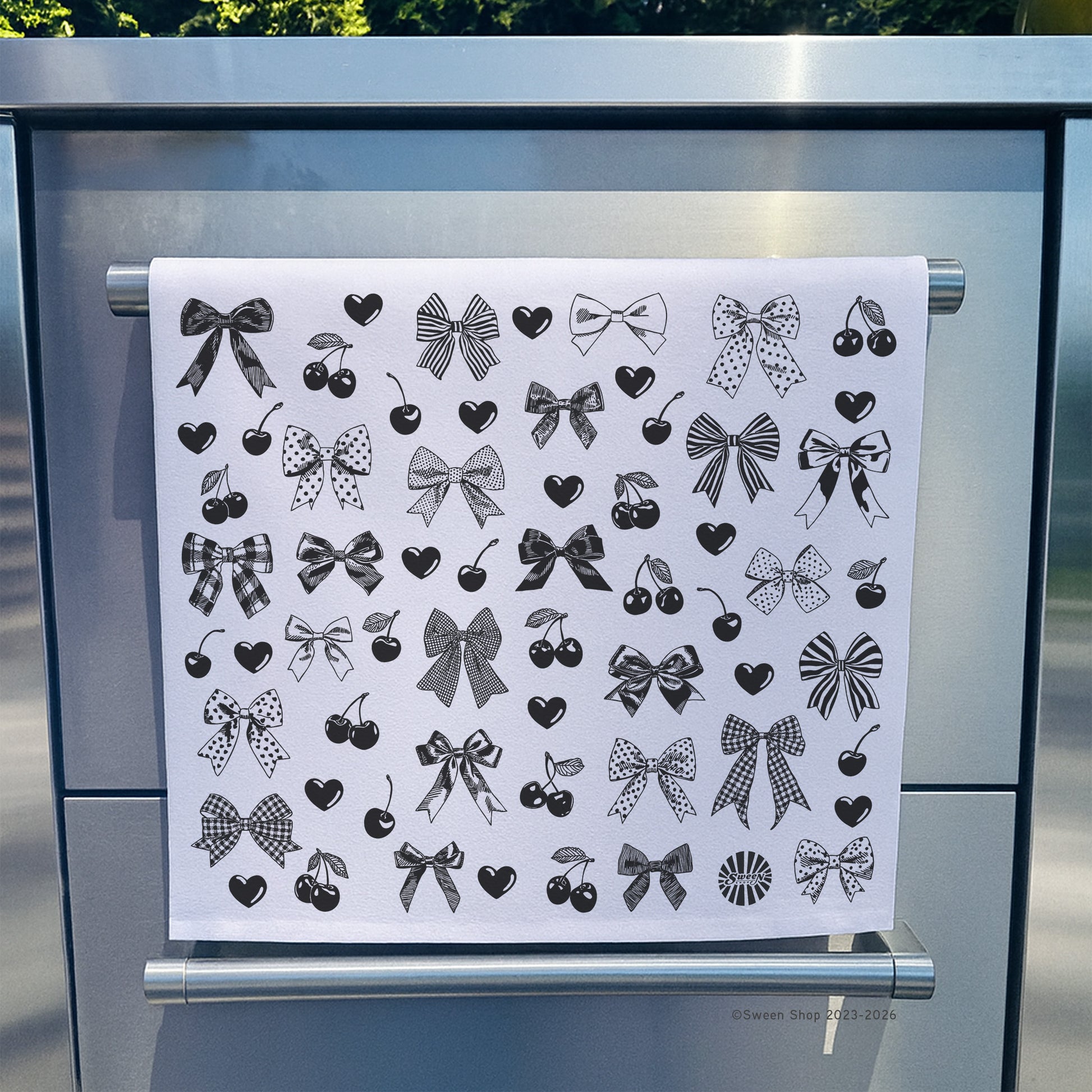 cotton kitchen towel with bow cherry and heart designs on a stainless steel appliance