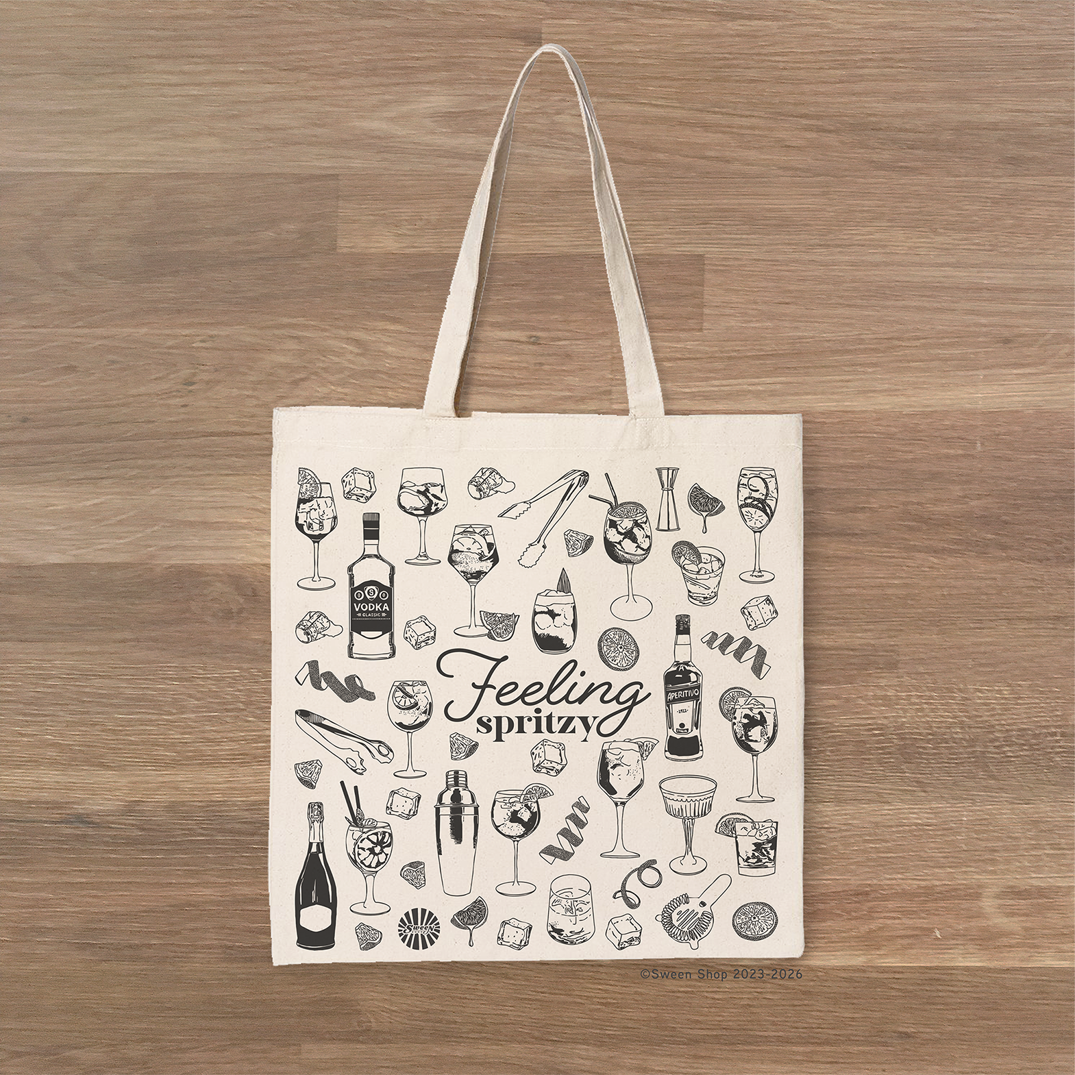Tote bag with aperol spritz cocktail drink-themed design and 'Feeling spritz' text on a wooden surface