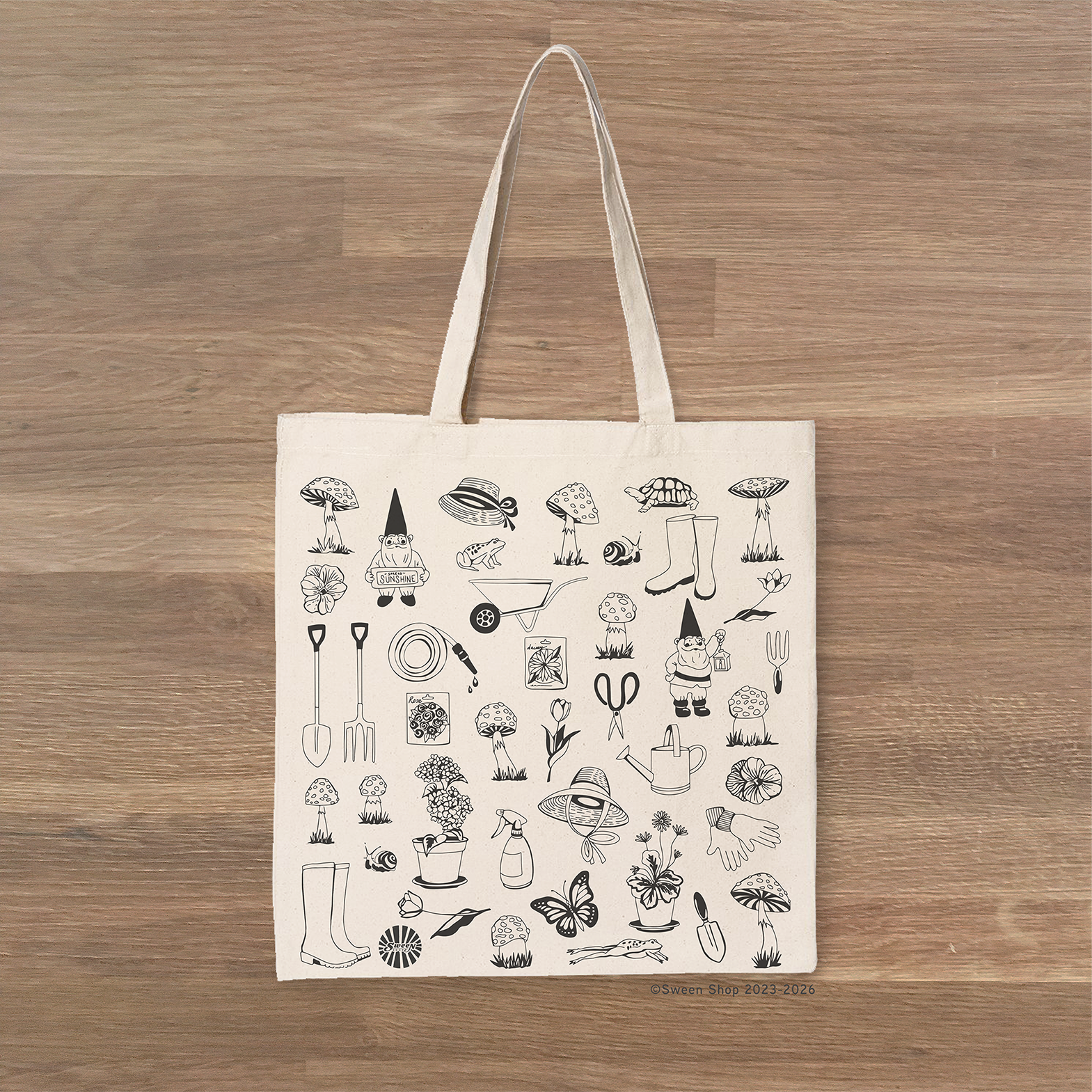 Tote bag with black garden themed illustrations on a wooden surface