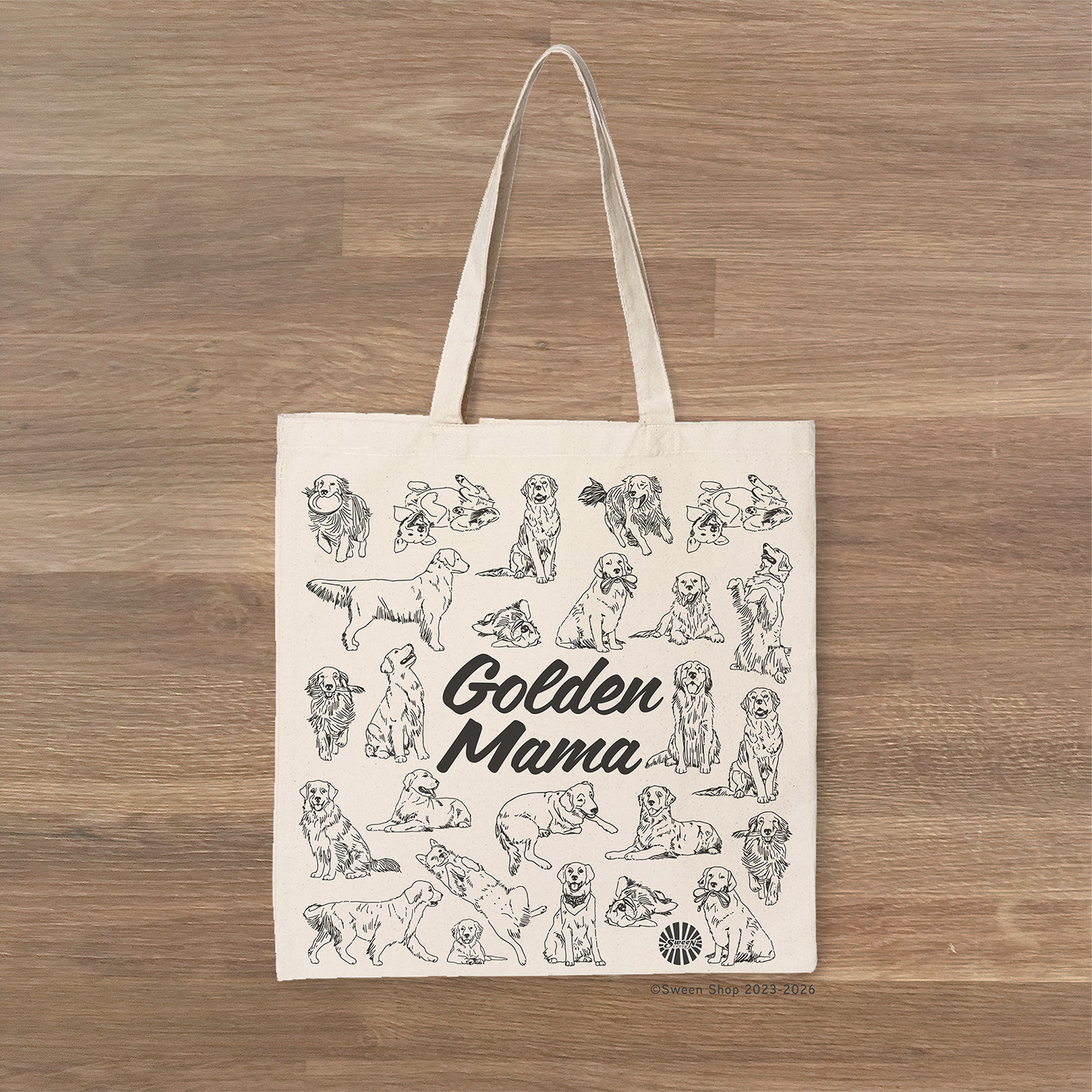 Tote bag with 'Golden Mama' text and illustrations of golden retrievers on a wooden surface
