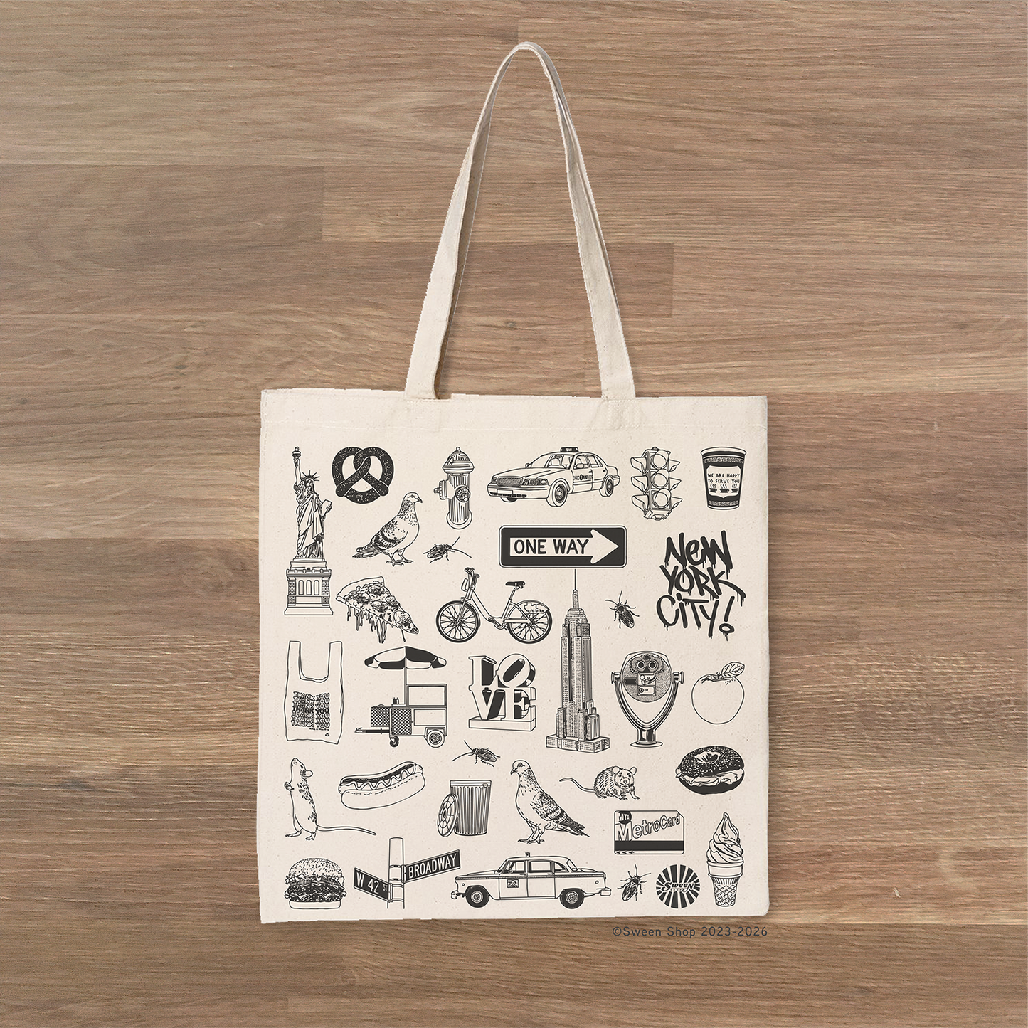 Tote bag with New York City-themed illustrations on a wooden surface