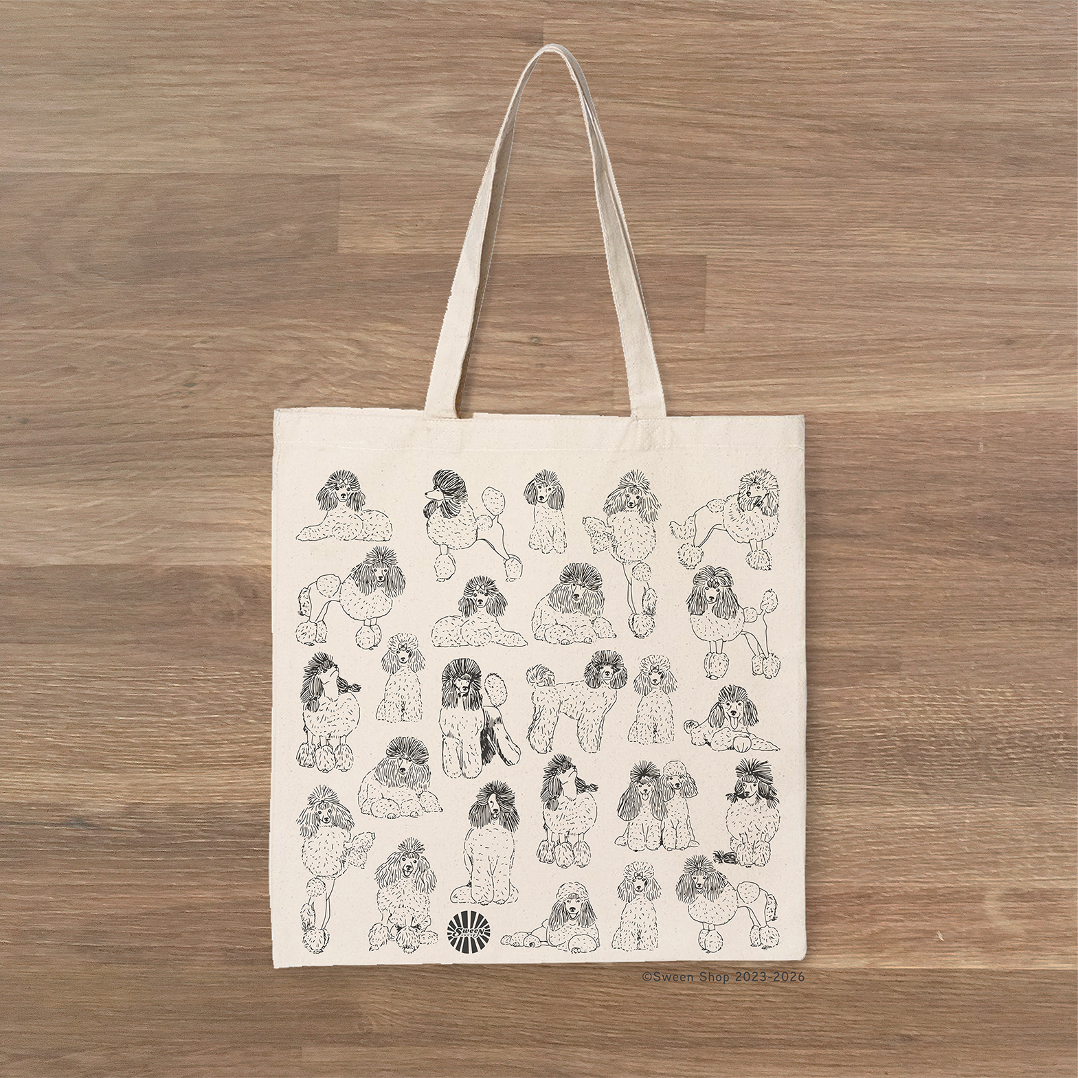 Tote bag with black illustrations of poodle pet dogs on a wooden surface