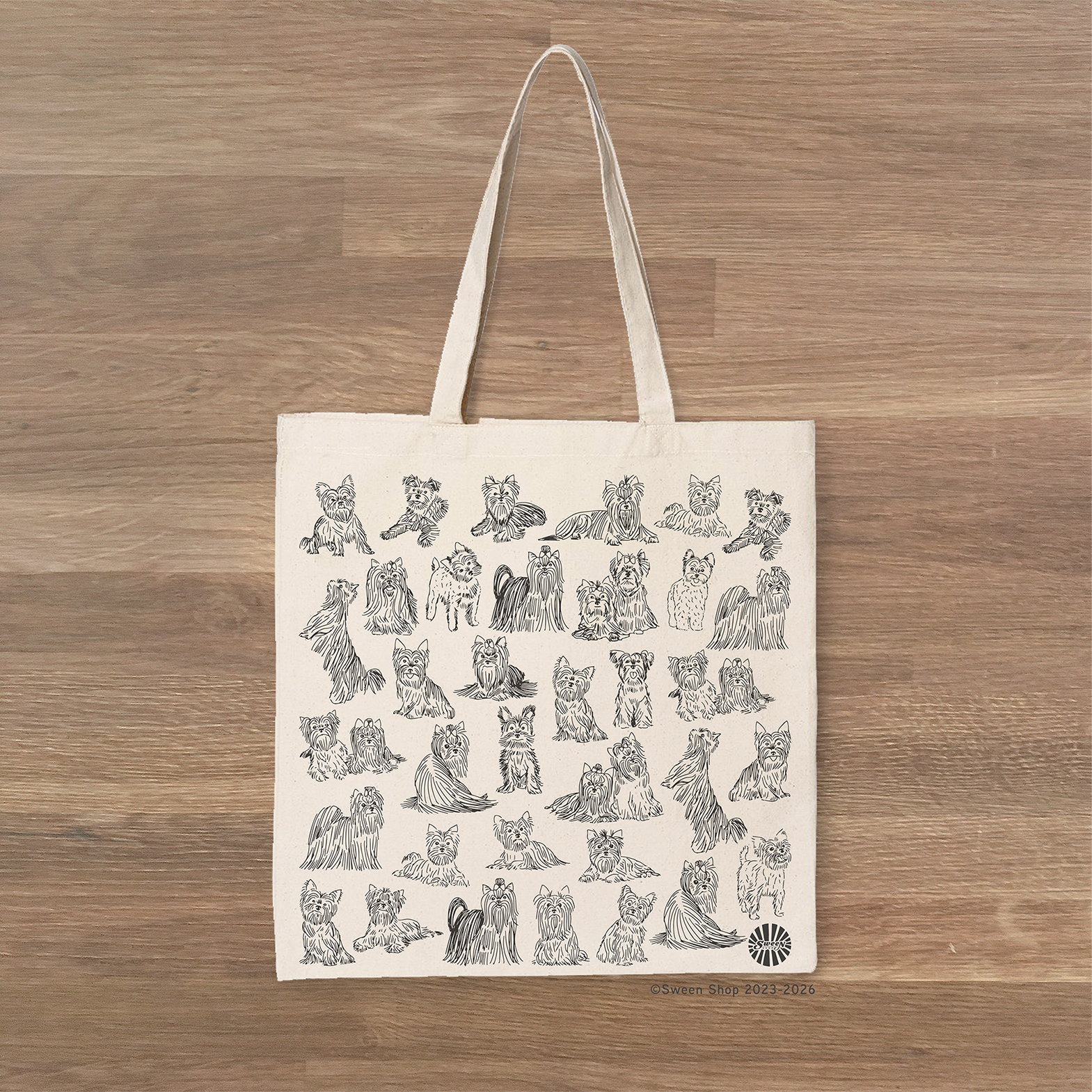 Natural cotton canvas Tote bag with black drawings of yorkshire terrier dogs on a wooden surface