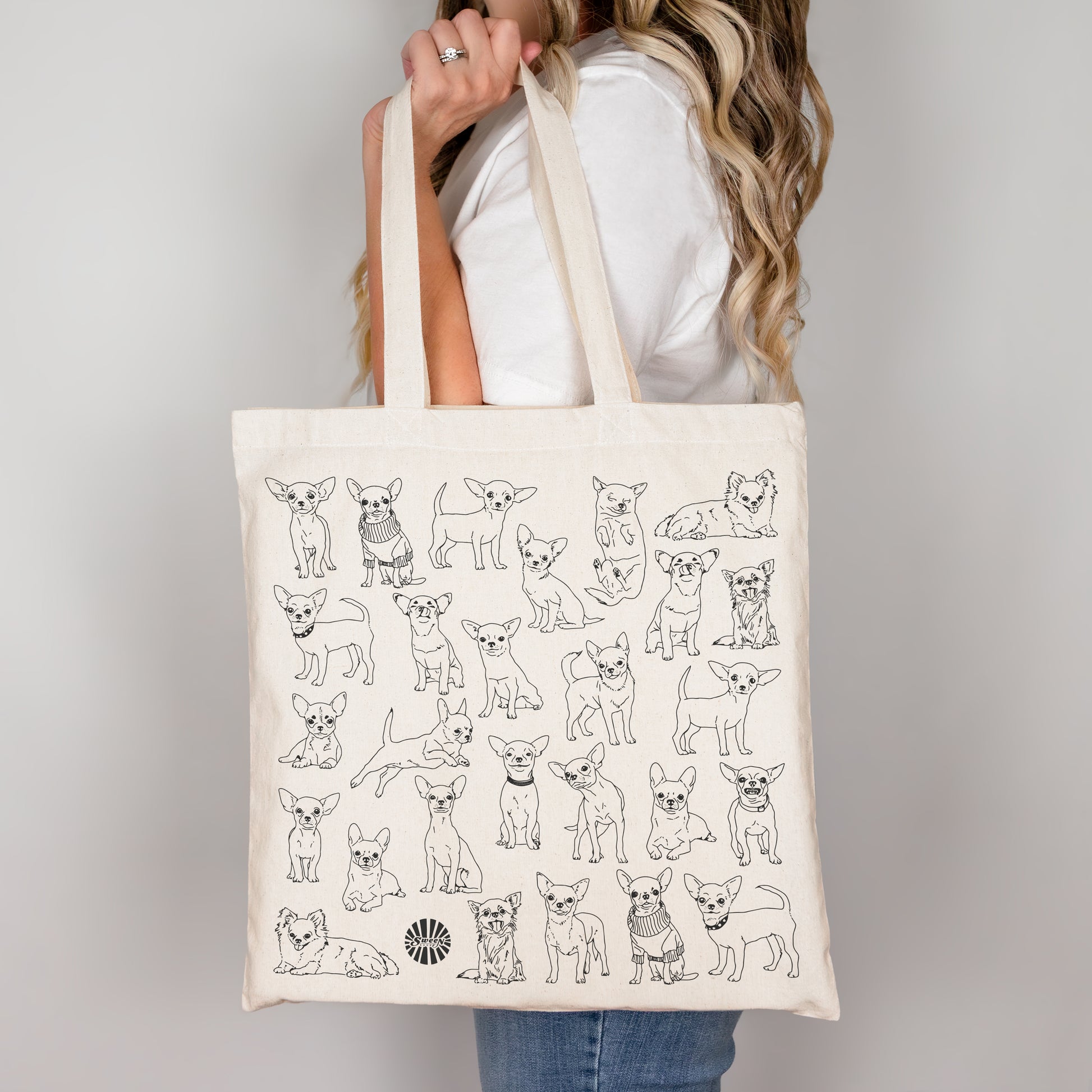 Tote bag with black line drawings of pet chihuahua dogs held by a person against a plain background
