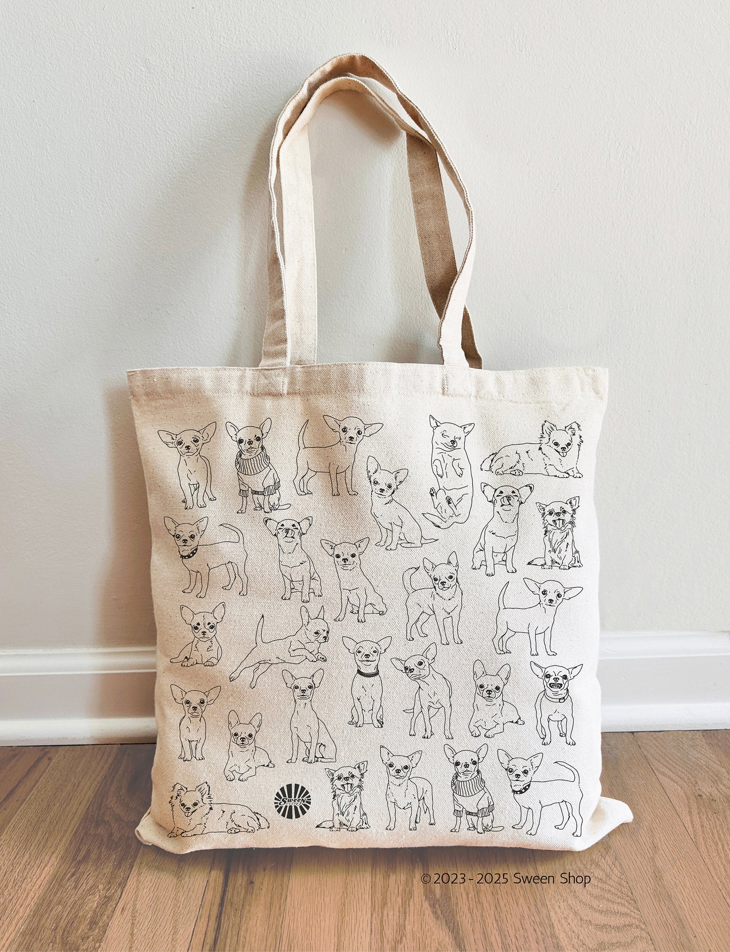 Tote bag with chihuahua pet dog illustrations on a wooden floor against a white wall