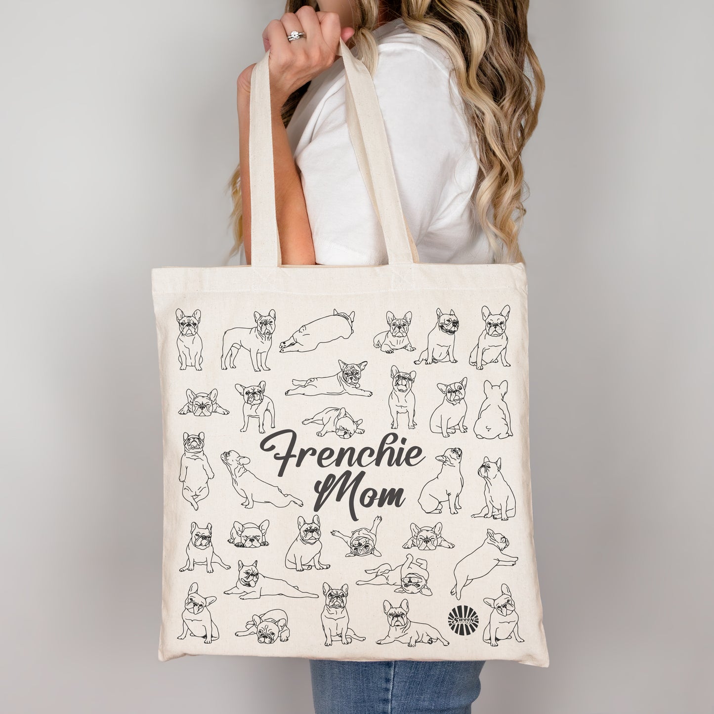 Tote bag with 'Frenchie Mom' text and french bulldog dog illustrations held by a person.