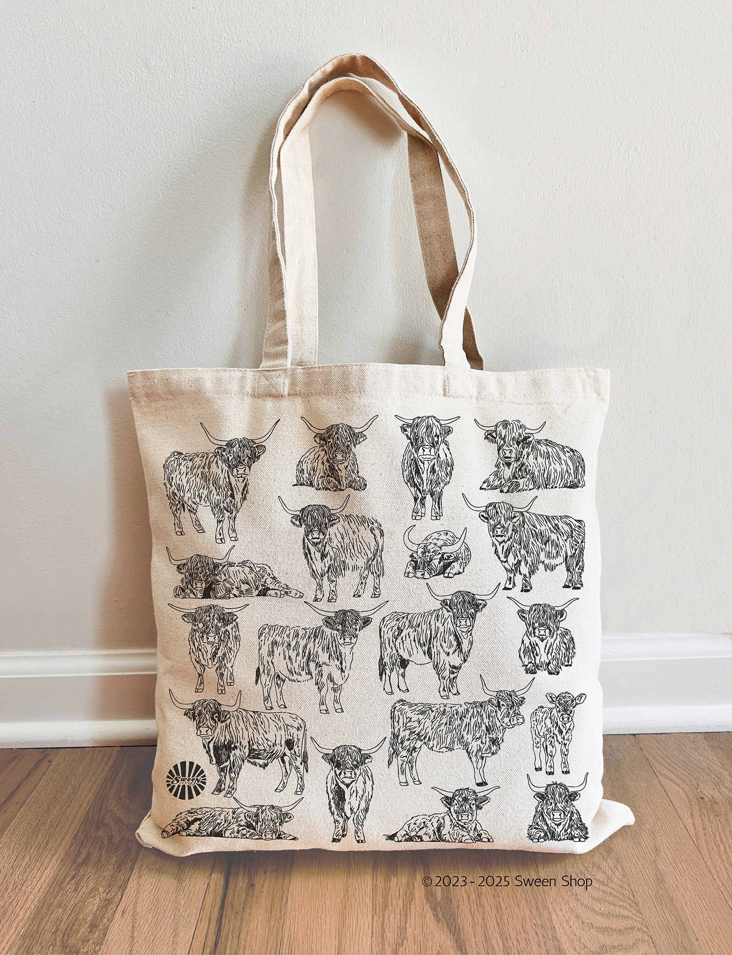 Tote bag with highland cow pattern on a wooden floor against a white wall