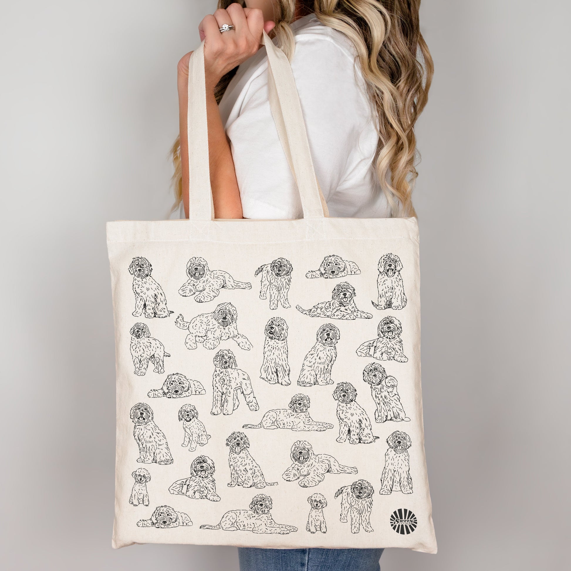 Tote bag with labradoodle pet dog pattern held by a person against a plain background
