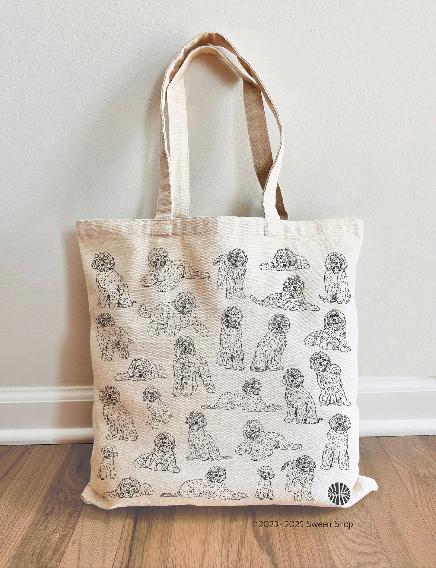 Tote bag with labradoodle pet dog pattern on a wooden floor against a white wall