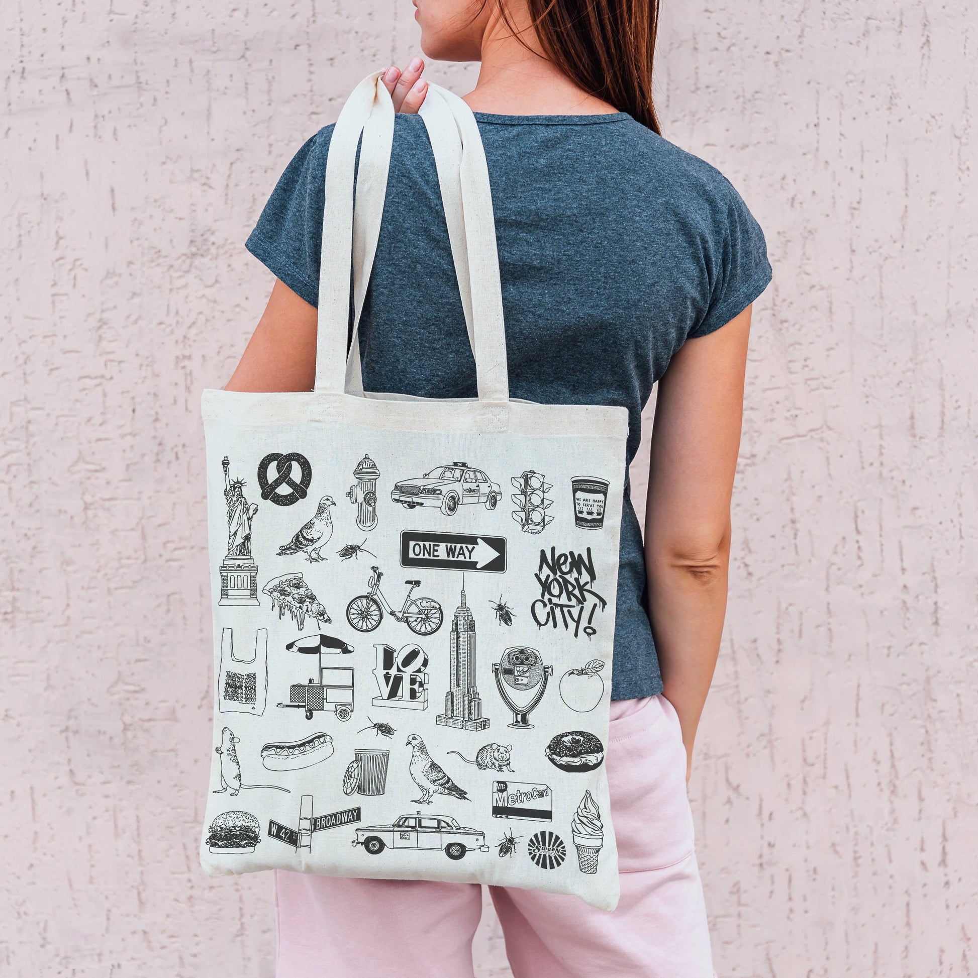 Person holding a tote bag with New york city themed illustrations against a light background