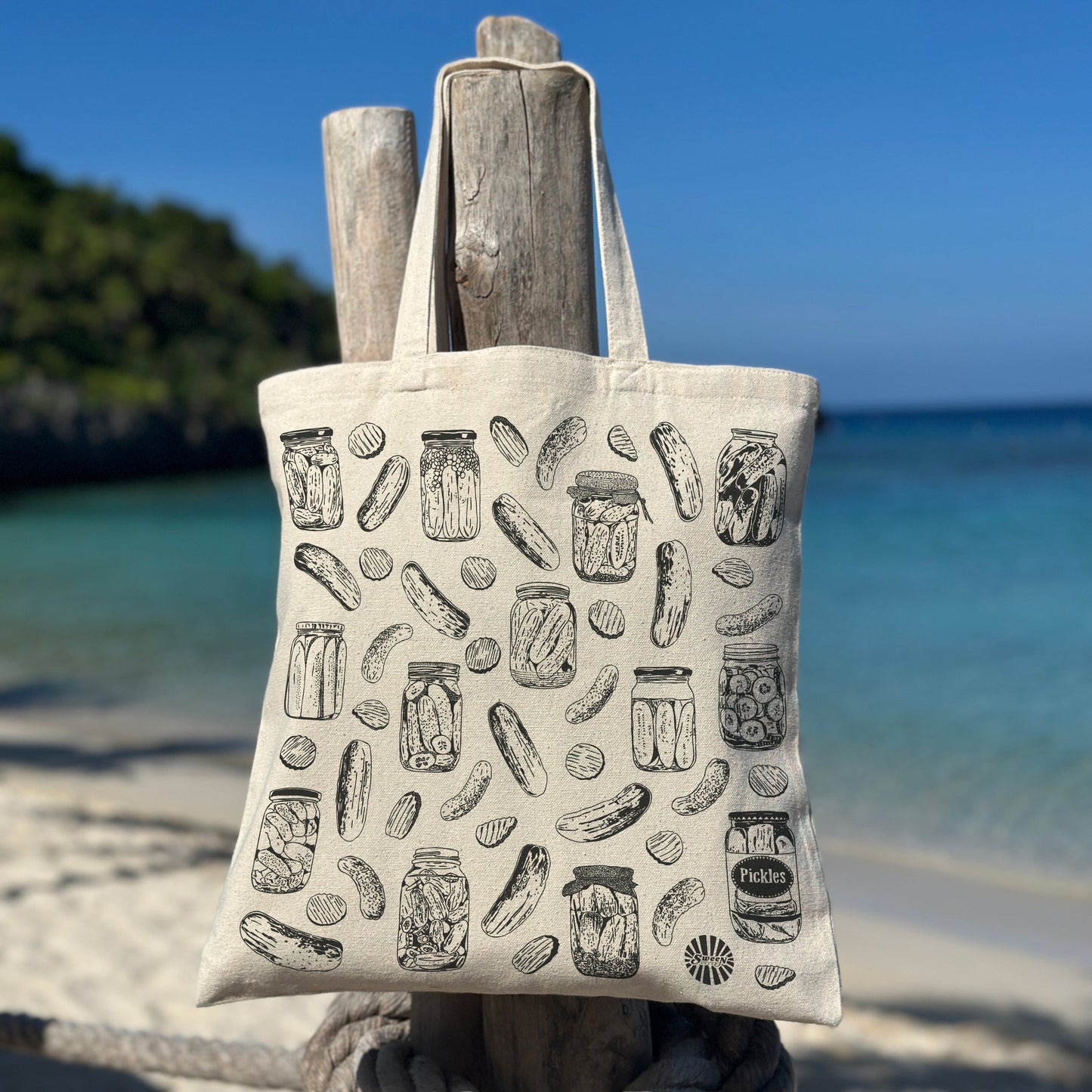 Tote bag with pickle jar pattern on a wooden post by the beach