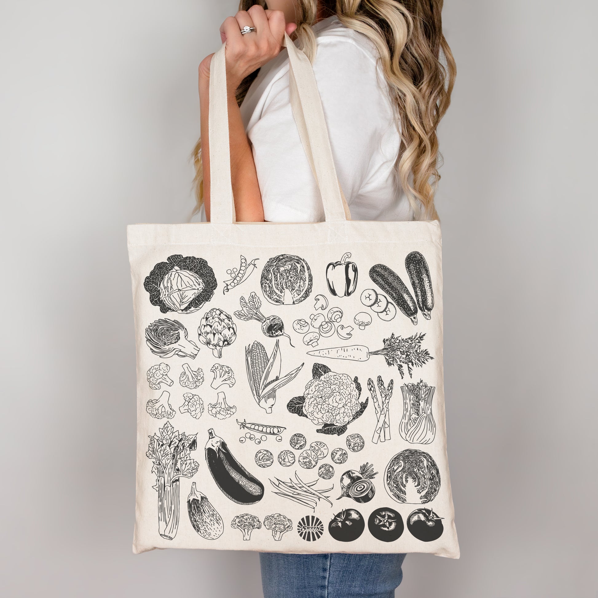 Natural cotton canvas Tote bag with black line drawing vegetable illustrations held by a person against a plain background
