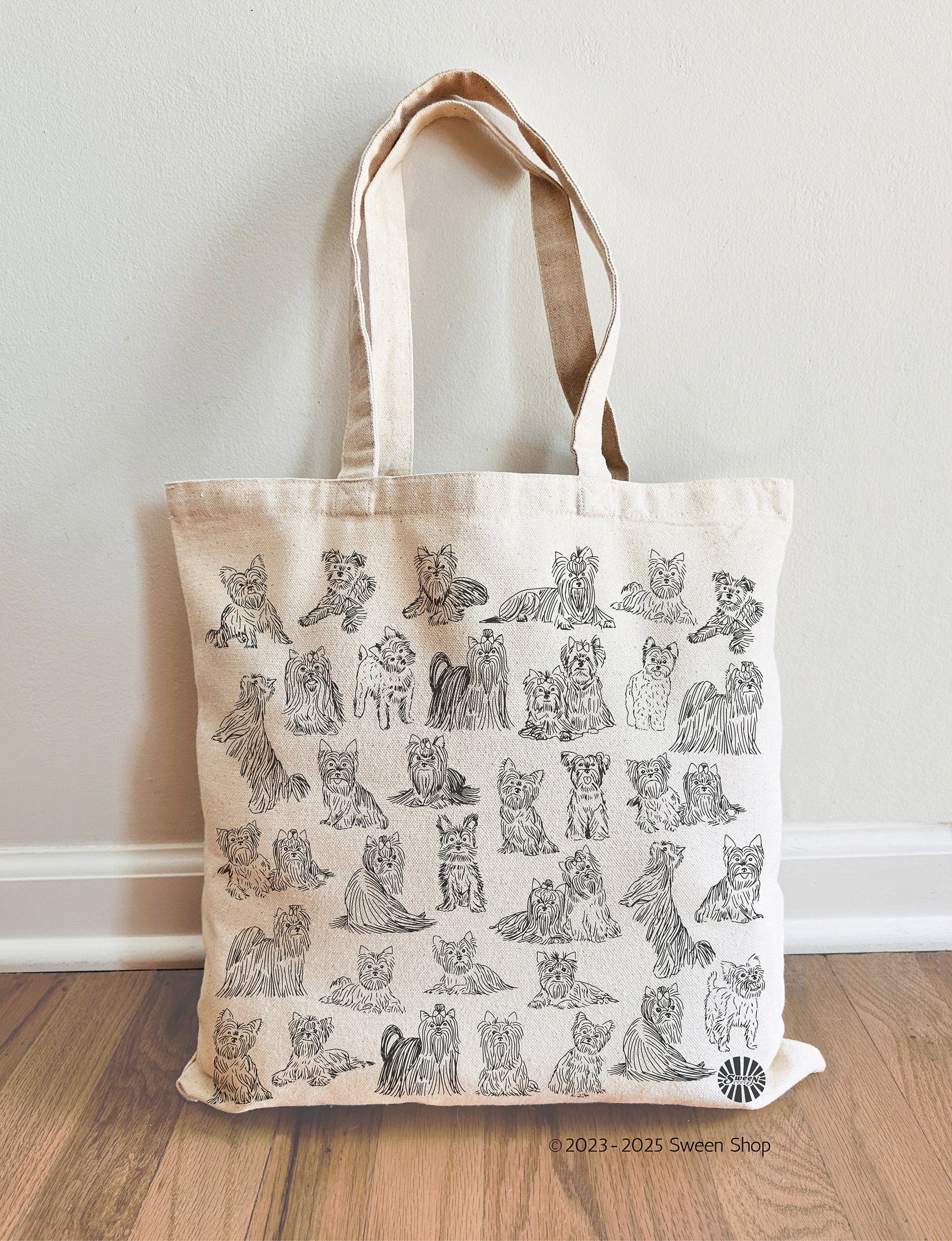 Natural Cotton canvas Tote bag with pet yorkie dog illustrations on a wooden floor against a white wall