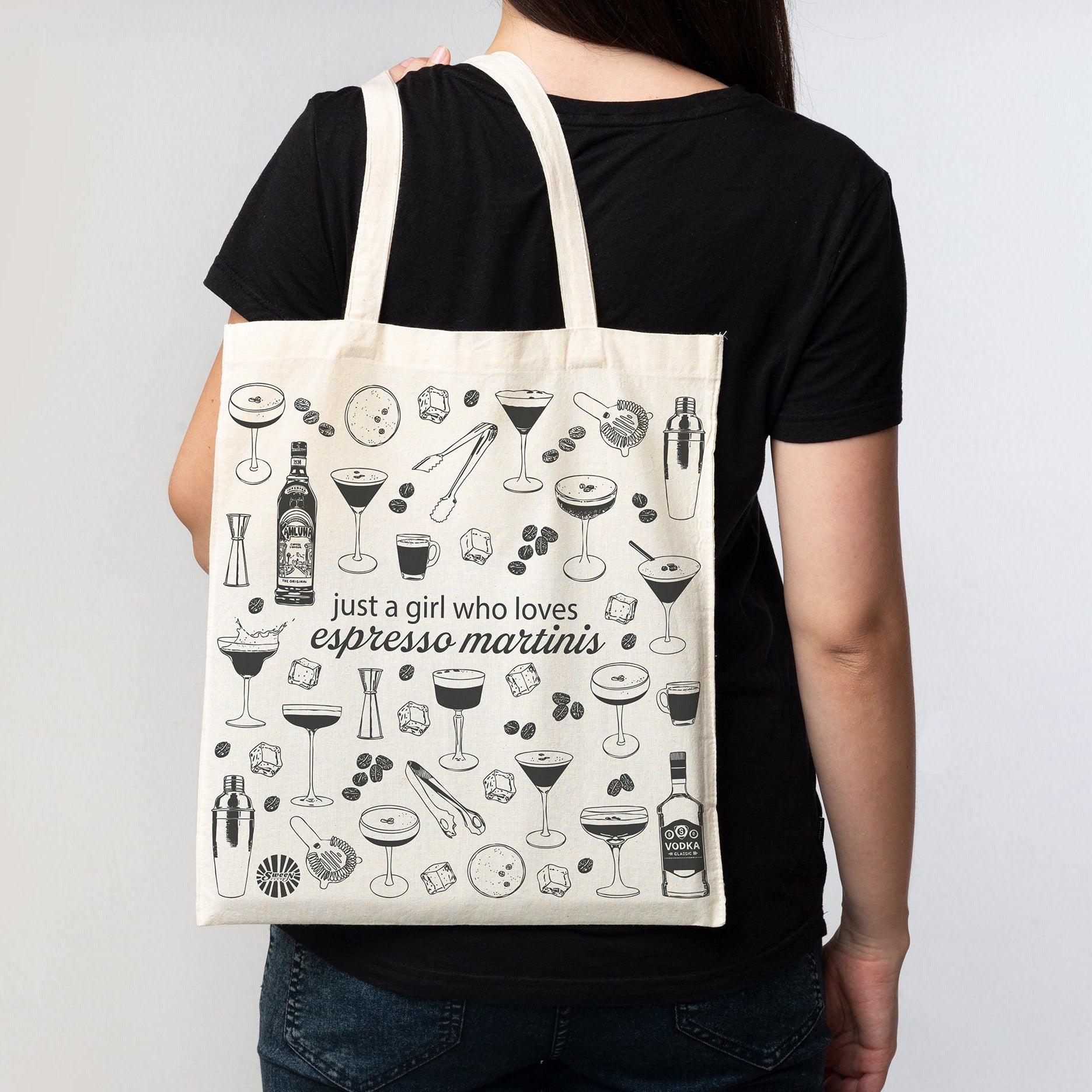 Person holding a tote bag with espresso martini cocktail drink illustrations and text.