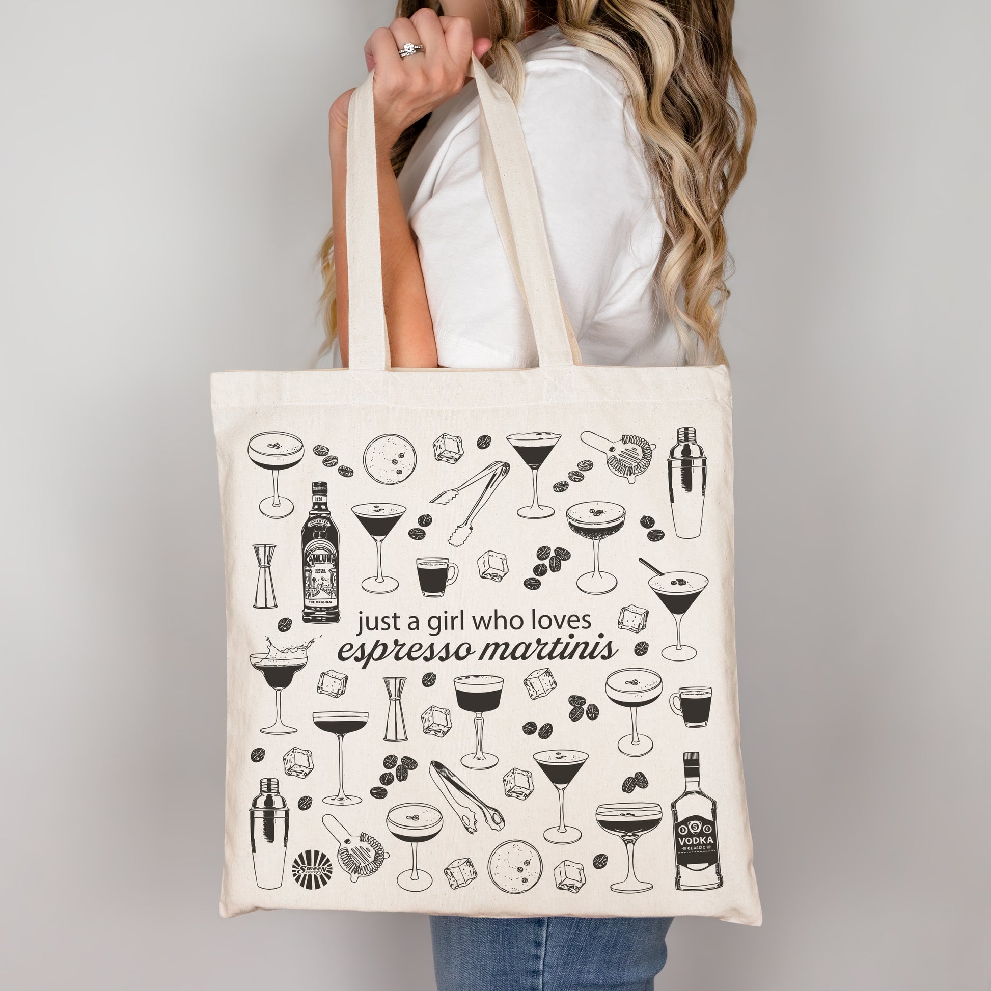 Person holding a tote bag with espresso martini cocktail illustrations and text.